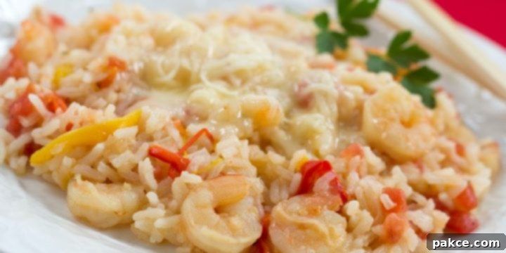 White plate with fluffy rice, succulent shrimp, diced tomatoes, and tender strips of bell peppers, topped with melted Monterey Jack cheese.