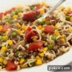 Easy Skillet Ramen 2 Ground beef, corn, peas, diced tomatoes, and ramen noodles on a white plate, ready to be served.