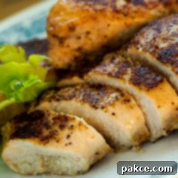 Golden Skillet Chicken Bake 3 Sliced, perfectly baked skillet chicken breast on a white plate, showcasing its golden crust and juicy interior.