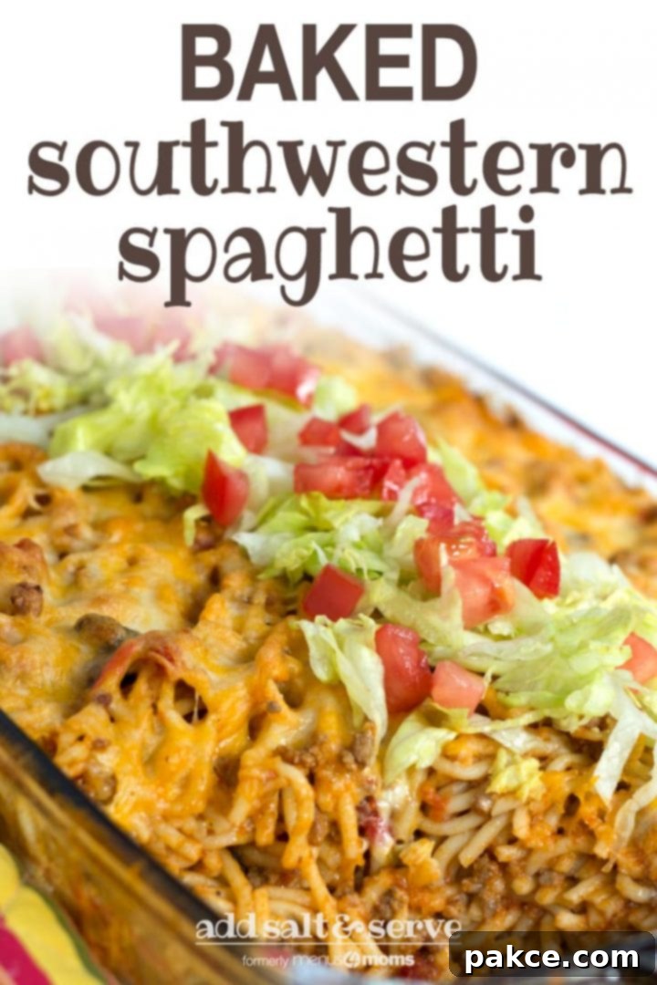 Clear casserole dish with spaghetti noodles, ground beef, and melted cheese, topped with shredded lettuce and diced tomatoes. Text baked southwestern spaghetti add salt & serve formerly menus4moms