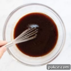 Signature Soy Garlic Beef Marinade 2 Large bowl of soy garlic marinade being whisked, showing the rich brown color and smooth texture