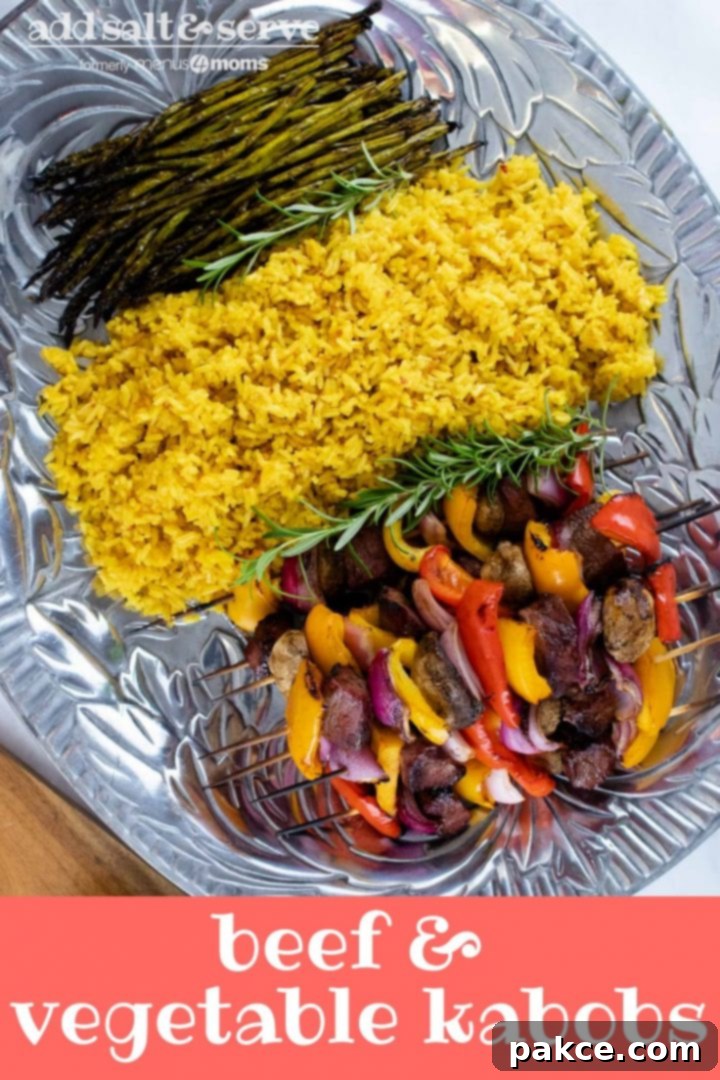 Large pewter platter showcasing a delectable spread of golden yellow rice, perfectly grilled asparagus, and colorful grilled beef kabobs with bell peppers, red onions, and mushrooms. Text overlay reads 