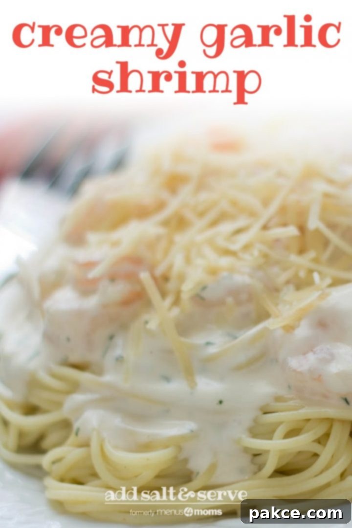 Angel hair pasta with alfredo sauce and shrimp, topped with shredded parmesan cheese, on a white plate. Text creamy garlic shrimp add salt & serve formerly menus4moms