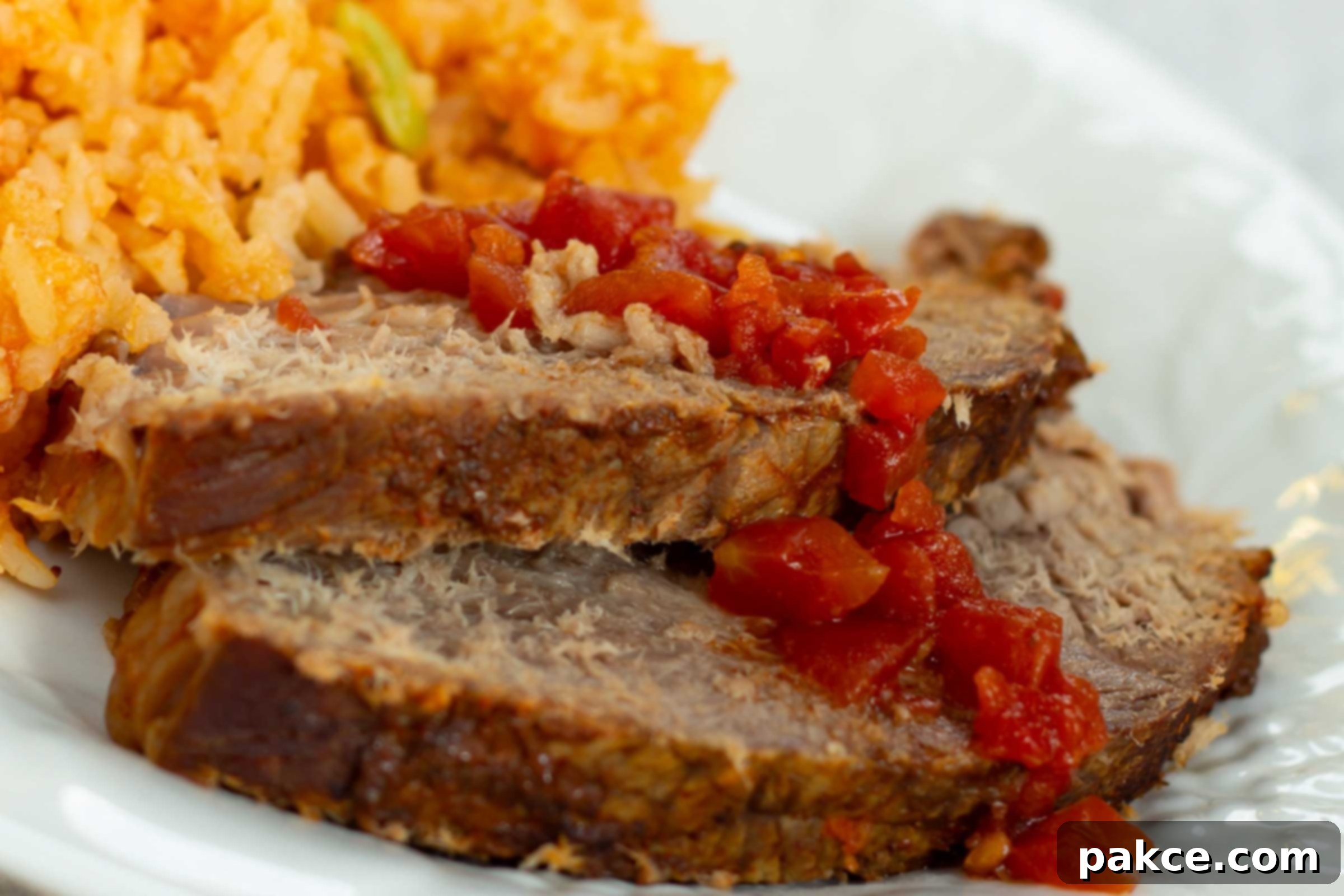 Tender Mexican Slow Cooker Pot Roast 4 Slices of pot roast on a plate beside Mexican rice.