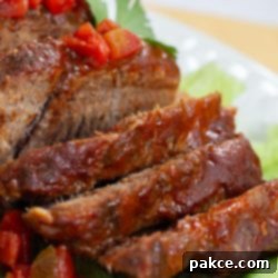 Tender Mexican Slow Cooker Pot Roast 5 Sliced pot roast with diced tomatoes on top and a red sauce.