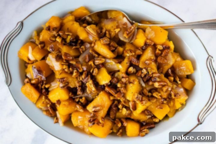 A bowl of vibrant roasted butternut squash with glistening candied pecans, ready to be served as a festive fall side dish.