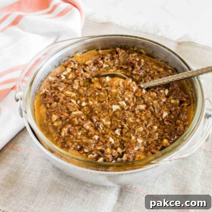 Sweet potato casserole with streusel topping served in a round dish, with a scoop removed, showing the creamy interior and crunchy topping