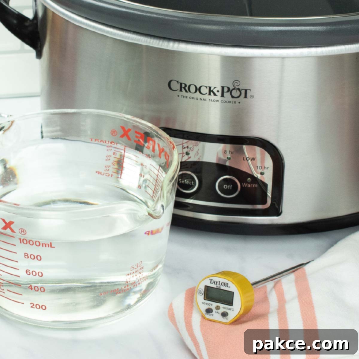 slow cooker with a measuring cup of water and a food thermometer