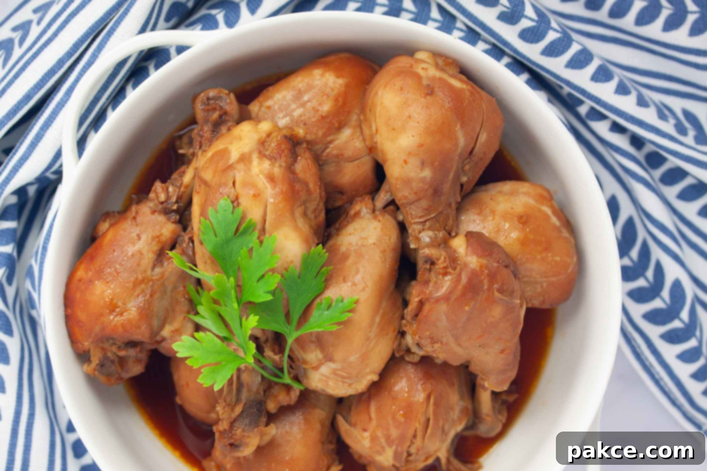 Cooked chicken legs with the meat falling off of the bones in a serving dish, garnished with fresh herbs and ready to be enjoyed.