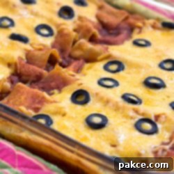 Ultimate Cheesy Ground Beef Enchiladas 2 Glass casserole dish with enchiladas topped with melted cheese and sliced black olives.