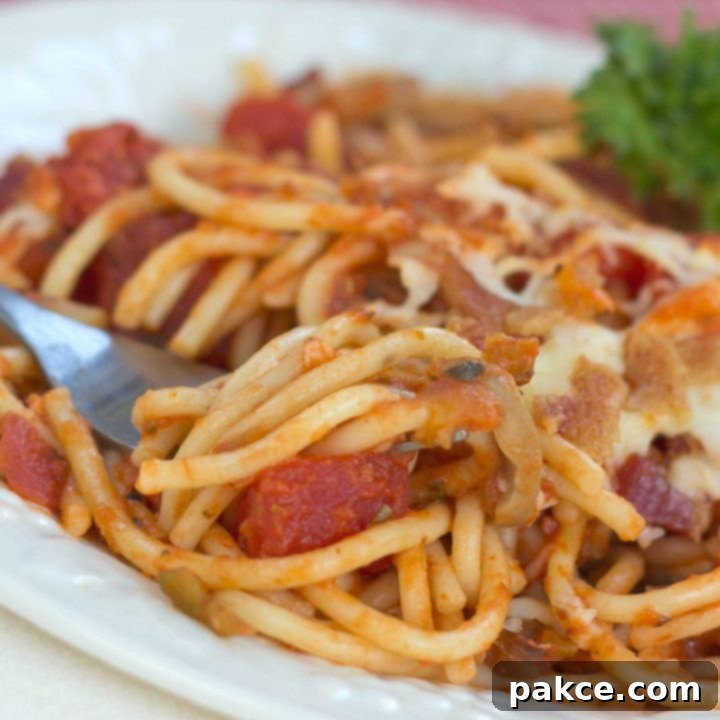 Baked spaghetti on white plate with a fork
