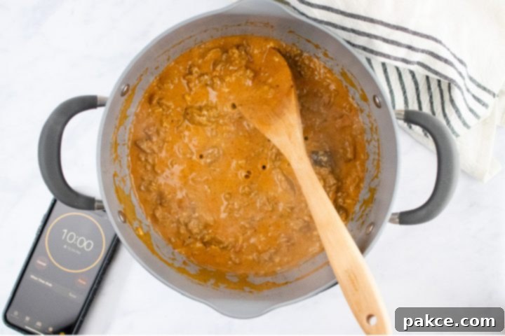 freezer-friendly-penne-pasta-bake-ip-4-min Overhead view of unbaked penne pasta bake topped with shredded cheese in a glass pan