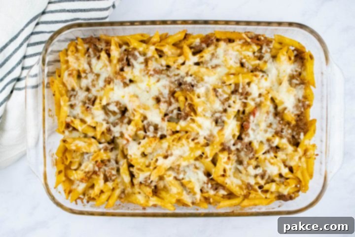 freezer-friendly-penne-pasta-bake-ip-7-min Overhead view of baked penne pasta bake topped with shredded cheese in a glass pan