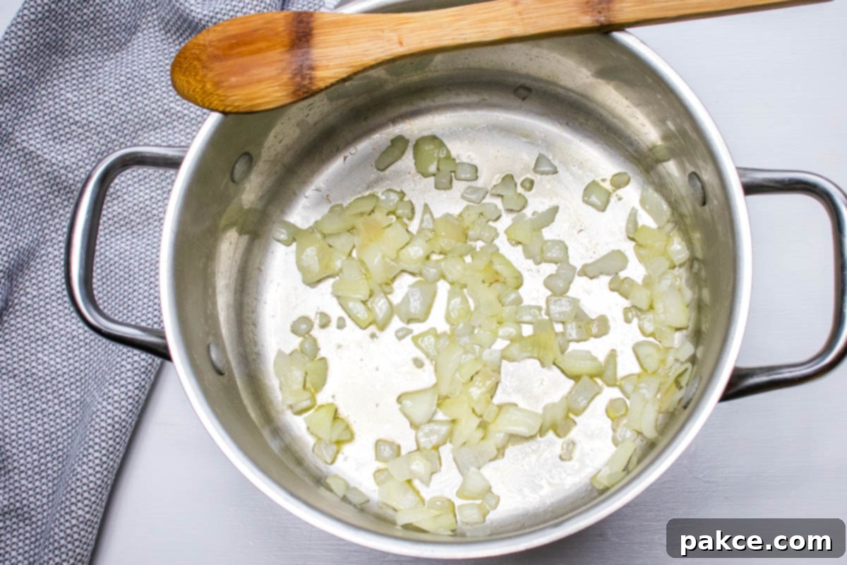 30 Minute Hash Brown Potato Soup Chopped onion being sautéed in a small amount of oil in a large soup pot over medium heat.