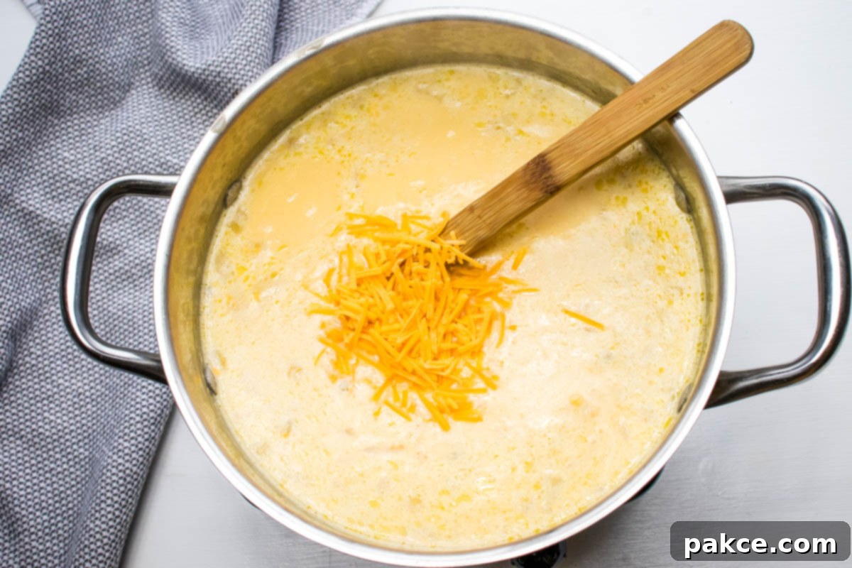 30 Minute Crispy Hash Brown Potato Soup 5 The potato soup with hash browns simmering in the pot, with shredded cheddar cheese just added and starting to melt.