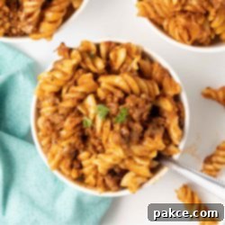Gooey Golden Spirals 10 Spiral pasta bake with cheese and ground beef served in white bowls.