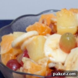 A Taste of Paradise 3 Grapes, chopped oranges, pineapples, and walnuts, and sliced bananas in a bowl.