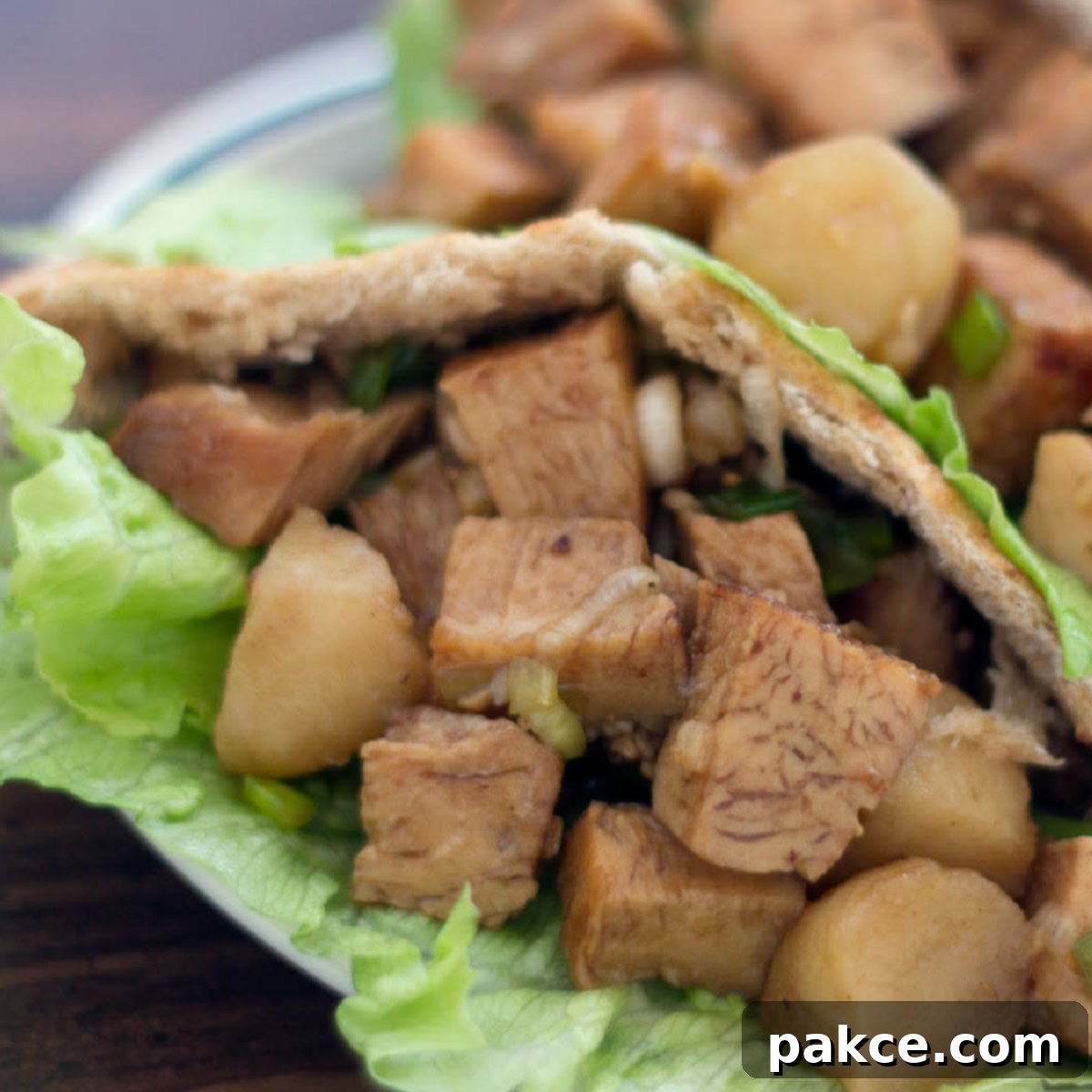 Delicious diced Asian-inspired chicken salad in a lettuce-lined whole wheat pita pocket, served on a white plate