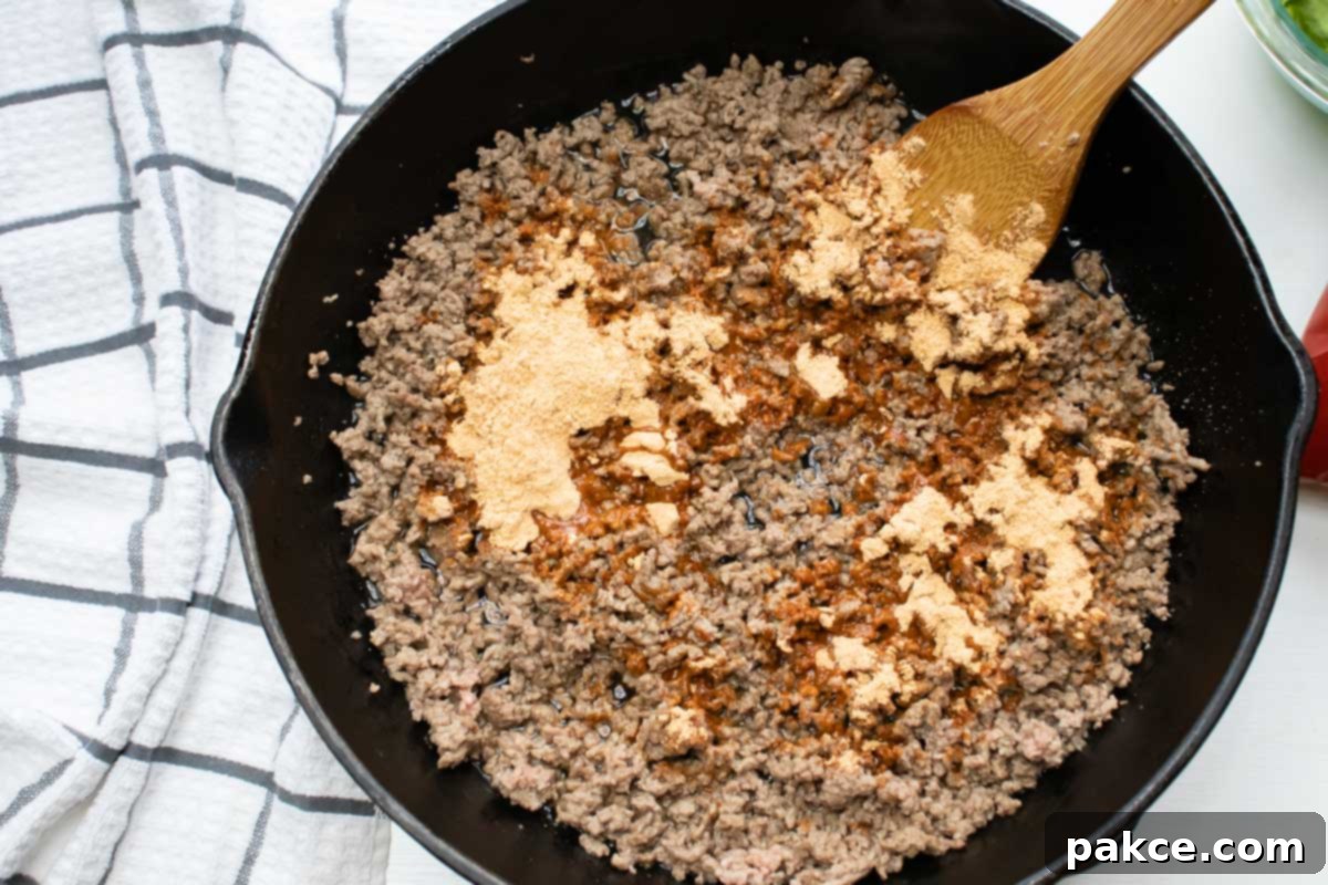 Taco Mac Salad Overhead shot of ground beef in a cast iron skillet with taco seasoning on top.