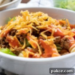 Southwestern Macaroni Toss 5 Bowl of seasoned ground beef, spiral pasta, lettuce, halved tomatoes, nacho cheese Doritos, and French salad dressing with shredded cheddar cheese on top
