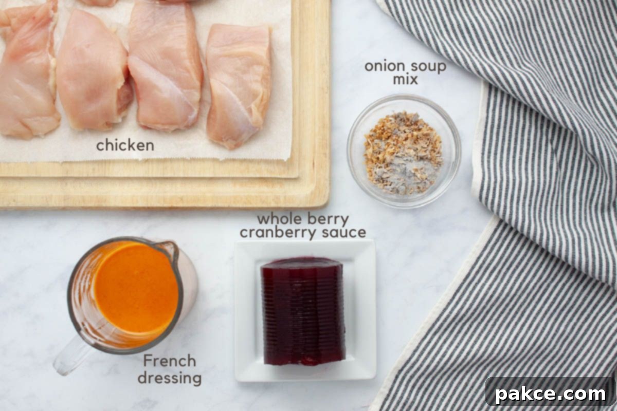 Slow Cooker Zesty Cranberry French Chicken 3 Pieces of uncooked boneless, skinless chicken breast on a cutting board, a measuring cup with French dressing, whole berry cranberry sauce on a plate, and a small bowl of onion soup mix on a counter with a grey striped tea towel to the side.