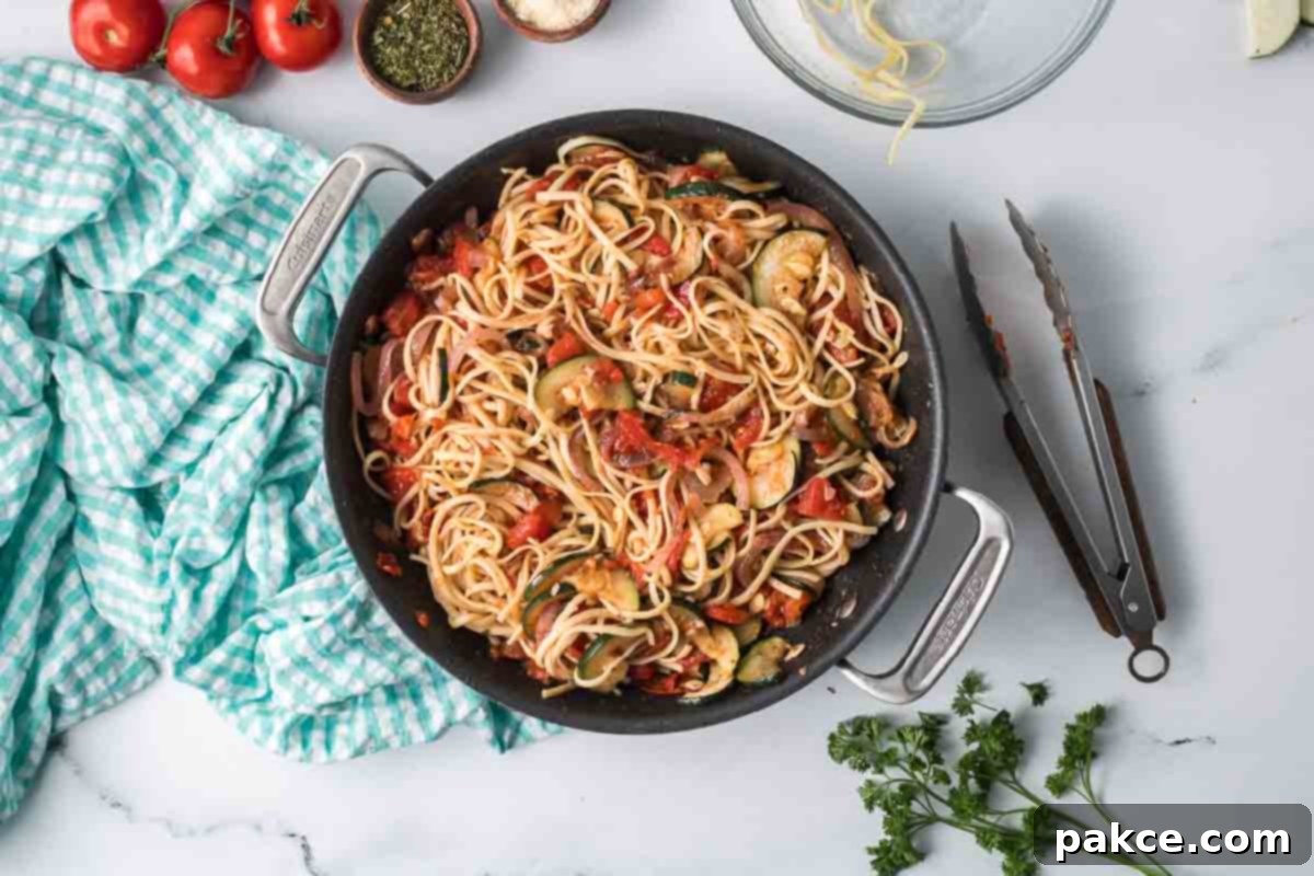 Spiralized Zucchini Linguine 9 Cooked zucchini linguine consisting of linguine with tomatoes, garlic, zucchini, onion, and herbs in a skillet.