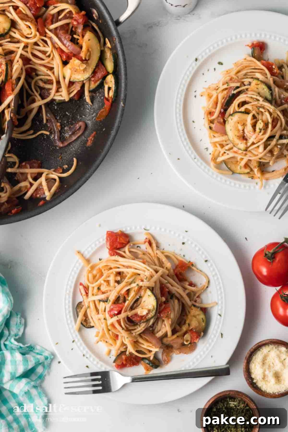 Spiralized Zucchini Linguine 10 Linguine with tomatoes, garlic, zucchini, onion, and herbs on a plate with skillet of remaining zucchini linguine recipe.