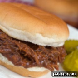 Slow Cooker Pulled BBQ Beef Sandwiches 3 Barbecue Roast Beef Sandwich garnished with two pickle slices.