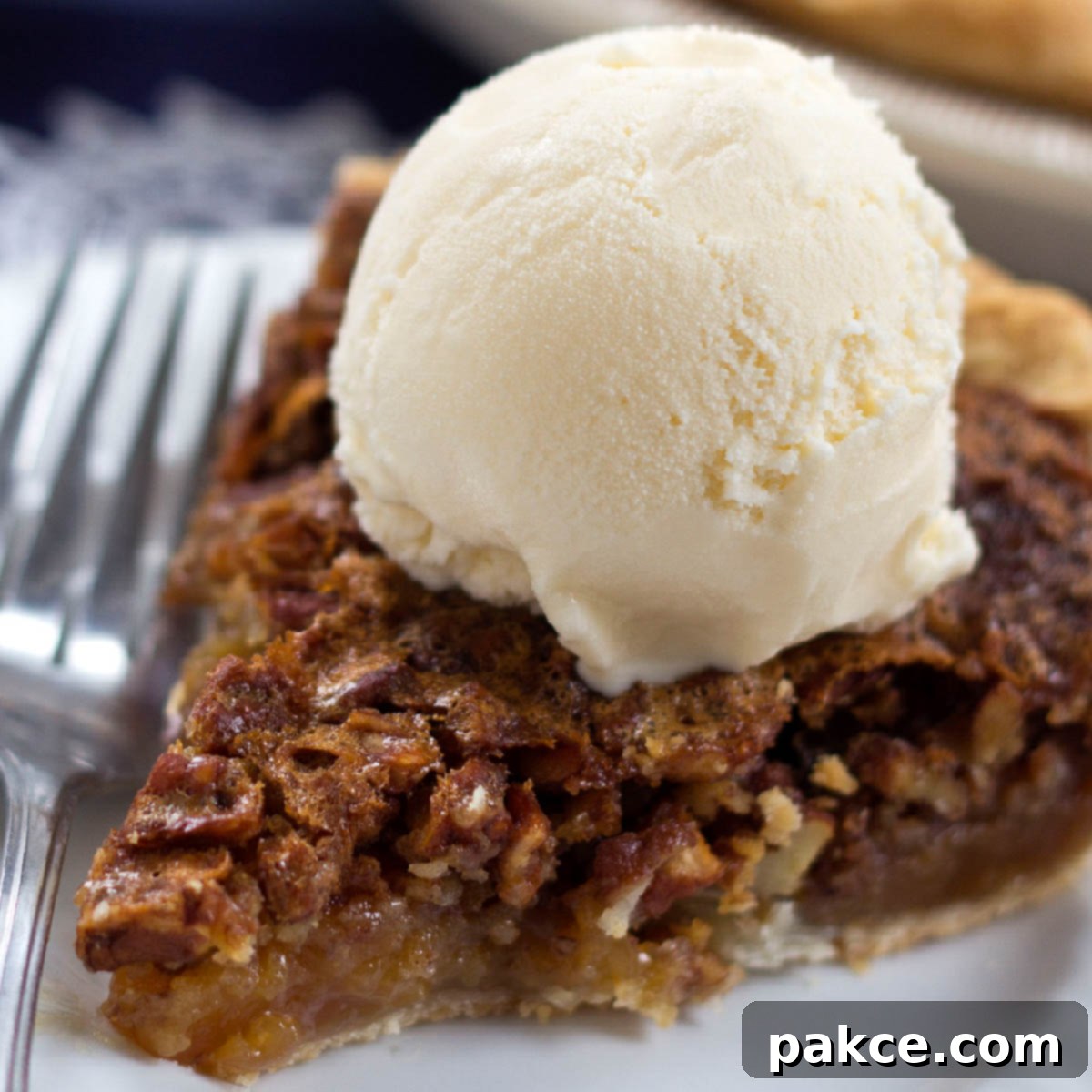Homemade pecan pie topped with a scoop of vanilla ice cream