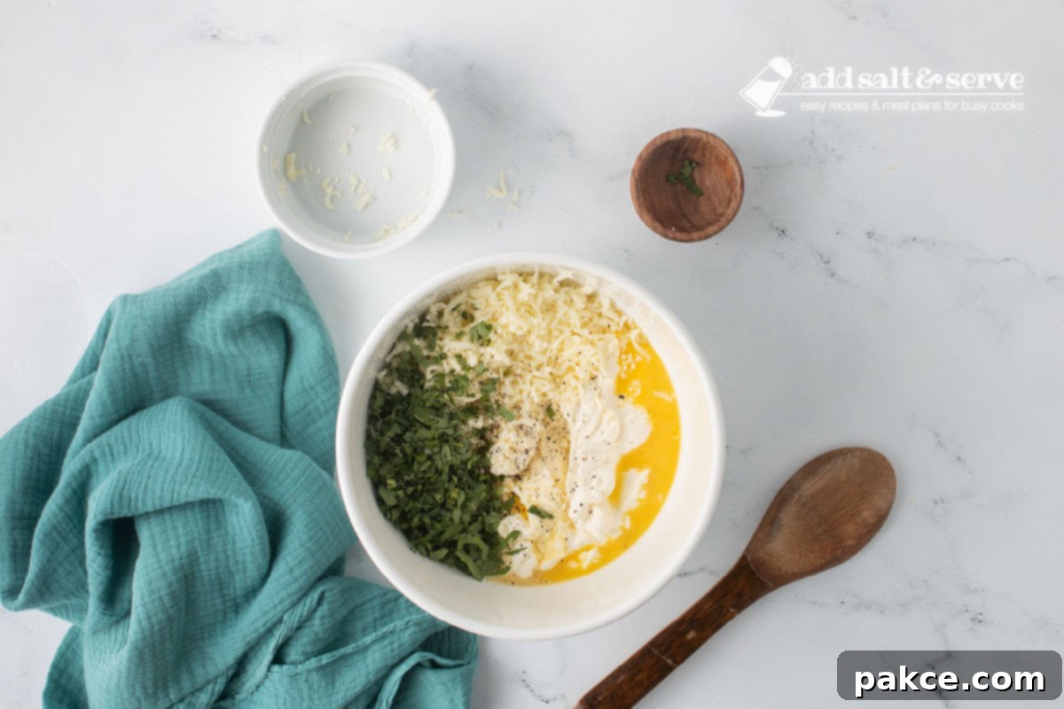 Creamy Alfredo Rotini Bake 4 A medium-sized bowl containing fresh ricotta cheese, raw eggs, shredded mozzarella cheese, minced fresh parsley, and sprinkles of salt and pepper, ready to be mixed together.