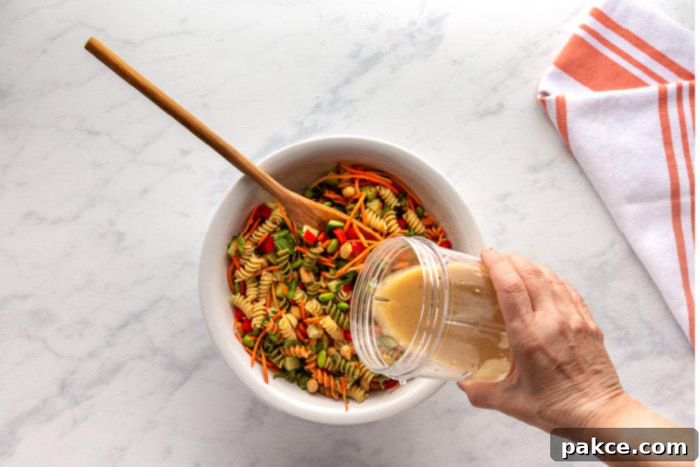 Thai Pasta Salad with Sesame Ginger Dressing 8 Pouring sesame-ginger dressing over Thai pasta Salad ingredients