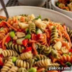 Thai Pasta Salad with Sesame Ginger Dressing 9 Colorful rotini pasta in a bowl with diced peppers and nuts, glistening with dressing