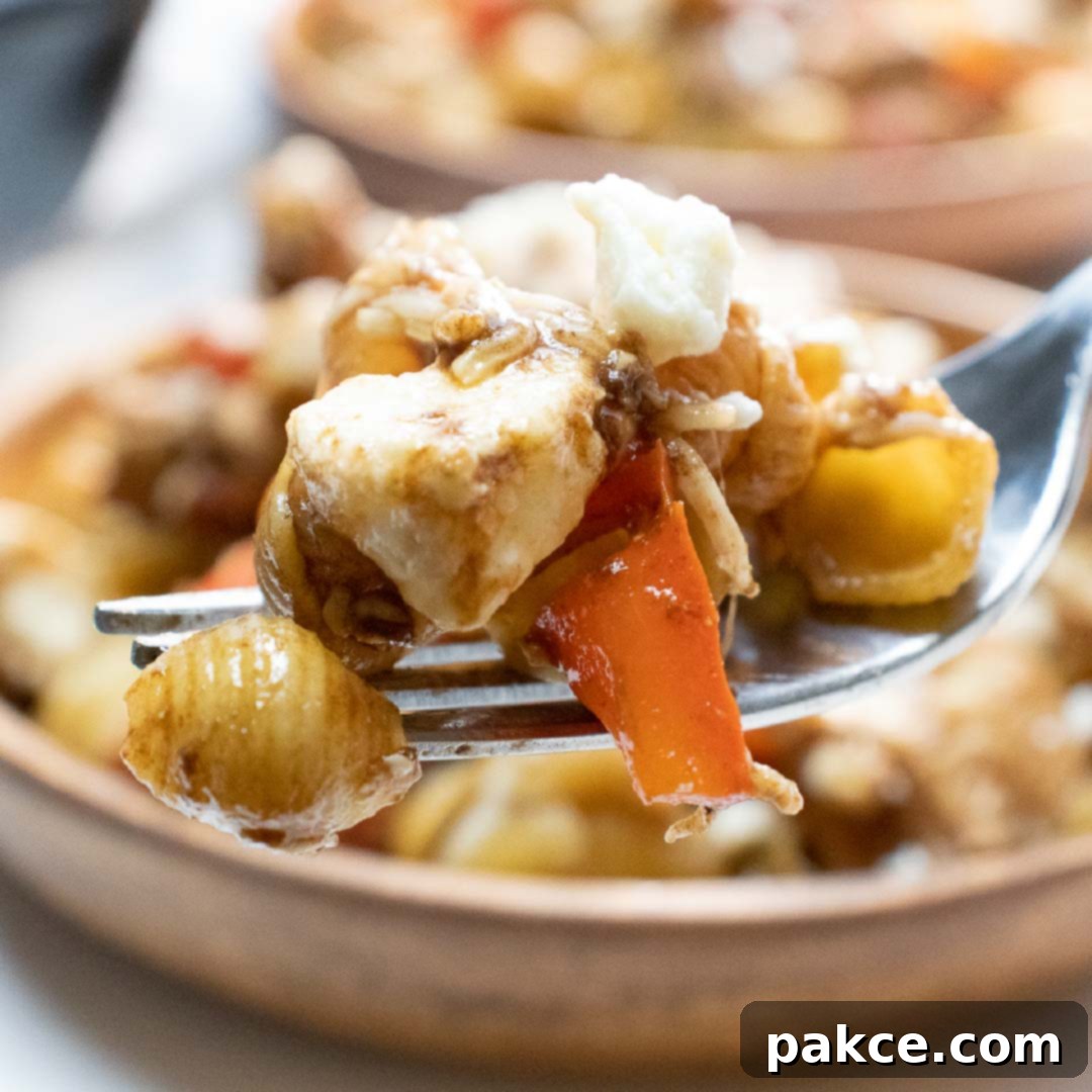 Forkful of shell pasta with tomatoes, feta cheese, and balsamic vinegar, ready to eat