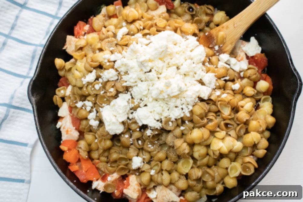 Mediterranean Chicken with Pasta Cast iron skillet with shell pasta, tomatoes, onions, feta cheese, and balsamic vinegar mixed in