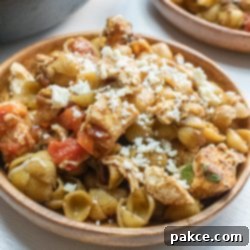 Vibrant Mediterranean Chicken Pasta 3 Bowl of shell pasta with tomatoes, feta cheese, and balsamic vinegar, garnished with fresh basil