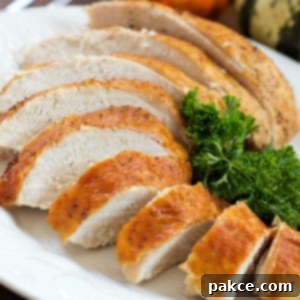 Foolproof Roast Turkey and Gravy 3 Close-up of golden brown, sliced roasted turkey breast garnished with parsley on a white plate