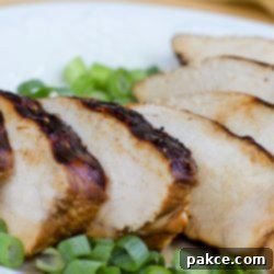 Make-Ahead Marinated Grilled Chicken 3 Sliced chicken breast on a white plate, garnished with chopped green onions.