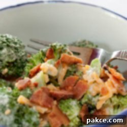 Creamy Broccoli Crunch 2 Broccoli, shredded cheddar cheese, bacon bits, and mayonnaise in a bowl with a fork.