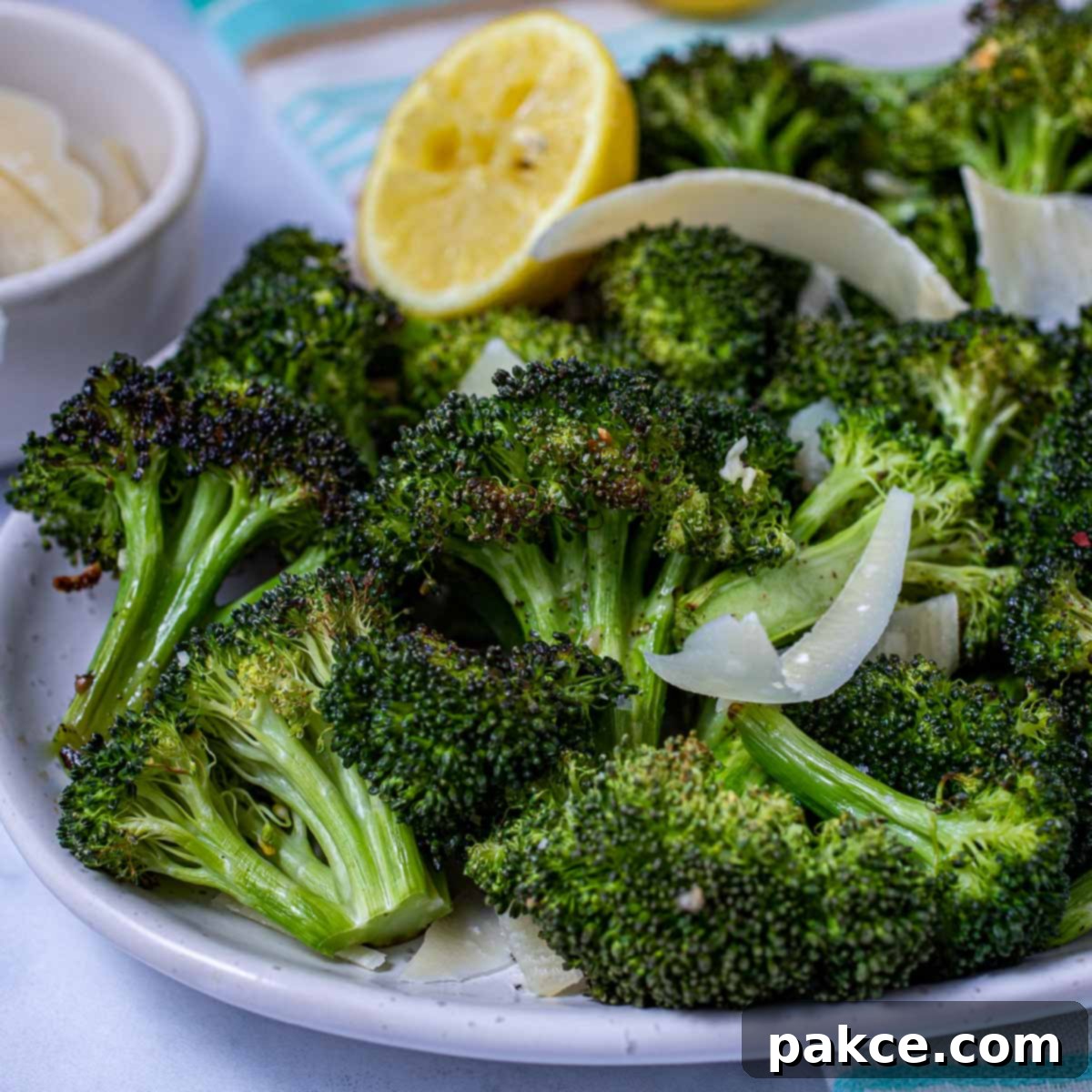 Roasted broccoli florets on a plate, garnished with a lemon half, showcasing perfect crispness and golden-brown edges.