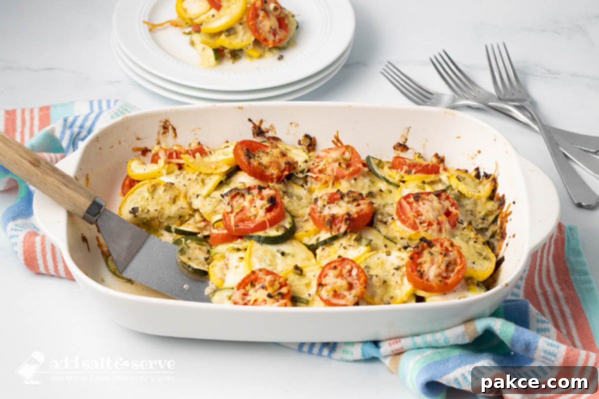Baked layered casserole of yellow squash, zucchini, and tomatoes with herbs and cheese in a baking dish.