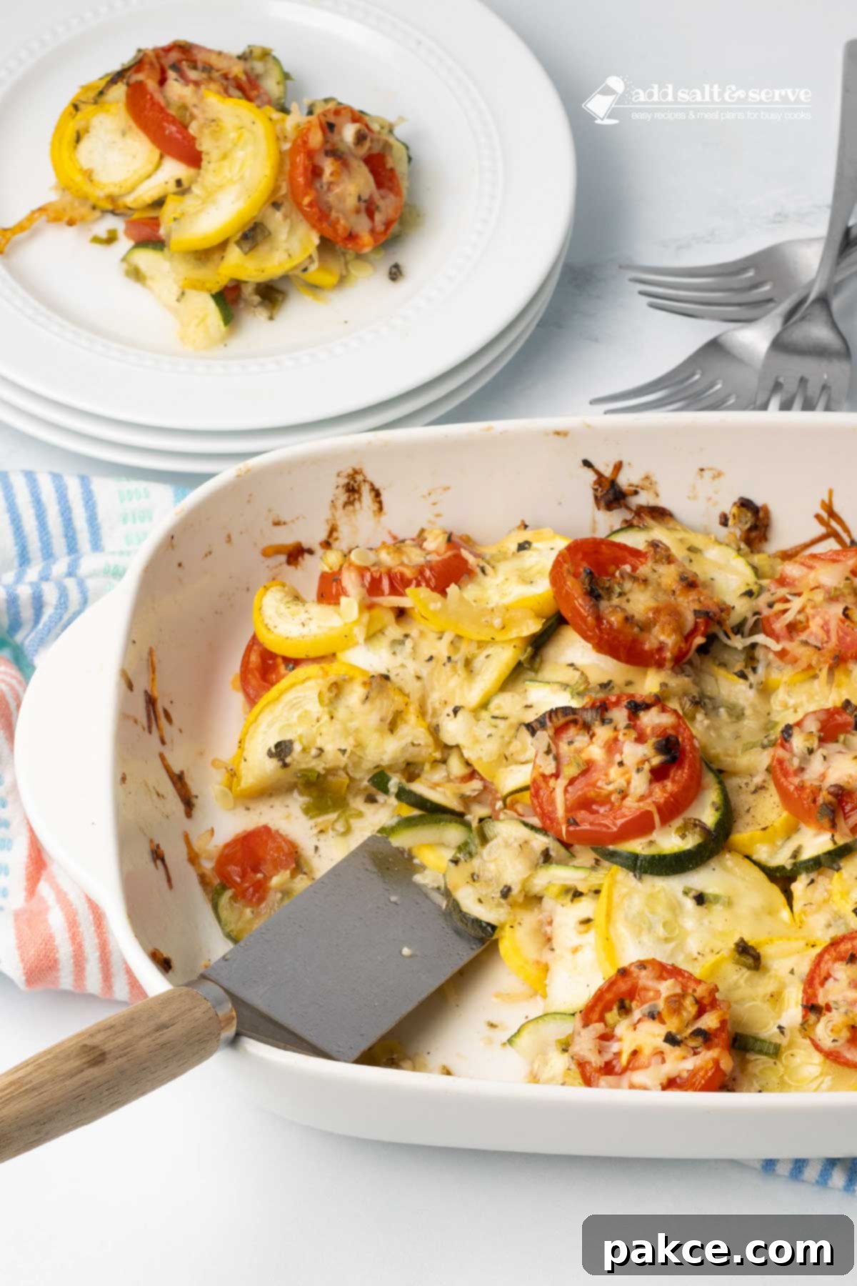 Garden Fresh Tomato and Squash Bake 6 Baked layered casserole of yellow squash, zucchini, and tomatoes with herbs and cheese in a baking dish with a serving on a plate beside the dish.