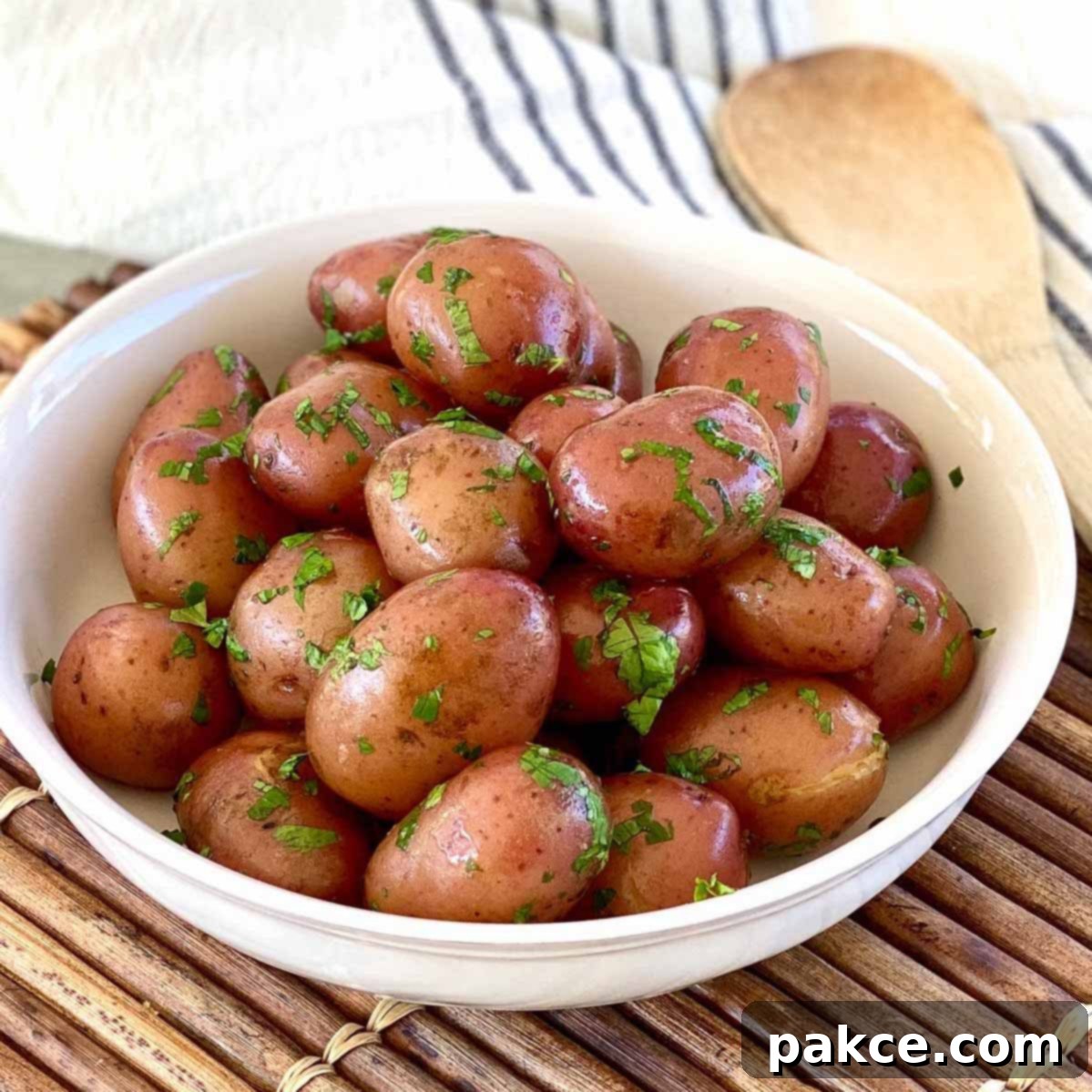 A bowl of perfectly boiled baby red potatoes, generously coated in melted butter and garnished with fresh chopped parsley, ready to be served as a delightful side dish.