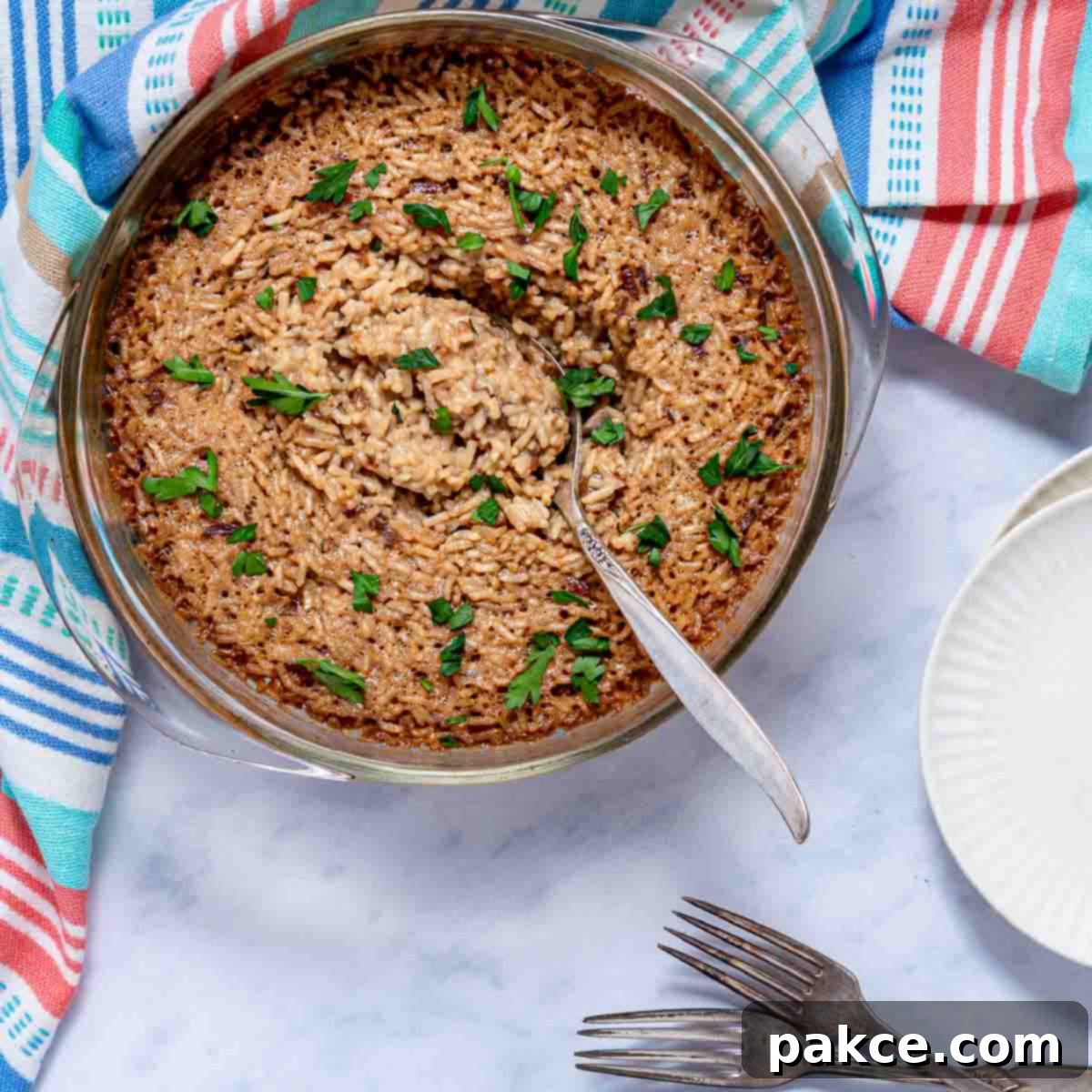 French Onion Rice garnished with parsley in a casserole dish with a serving spoon.