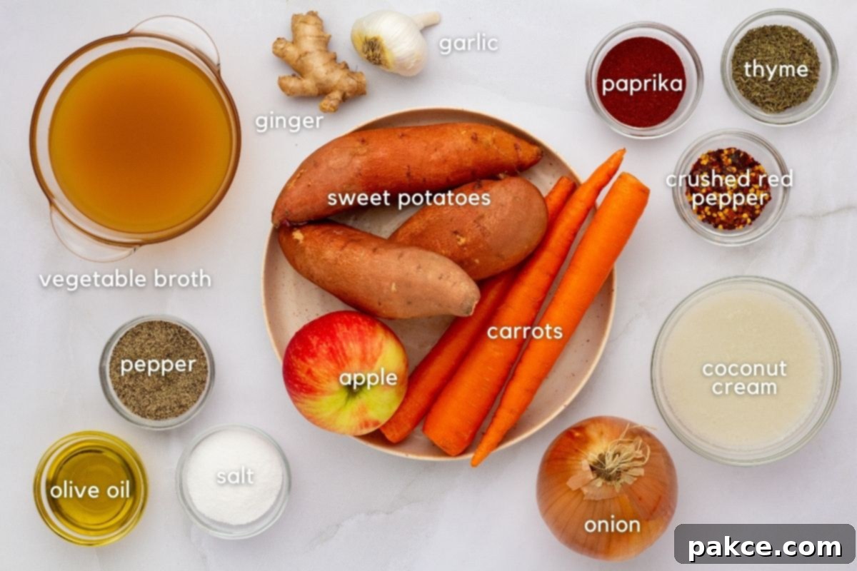 Golden Ginger Sweet Potato Carrot Soup 3 A vibrant selection of fresh ingredients for Carrot, Sweet Potato & Ginger Soup: vegetable broth, whole ginger root, garlic cloves, ground paprika, dried thyme, crushed red pepper flakes, olive oil, salt, pepper, a yellow onion, rich coconut cream, a sweet red apple, whole carrots, and plump sweet potatoes.