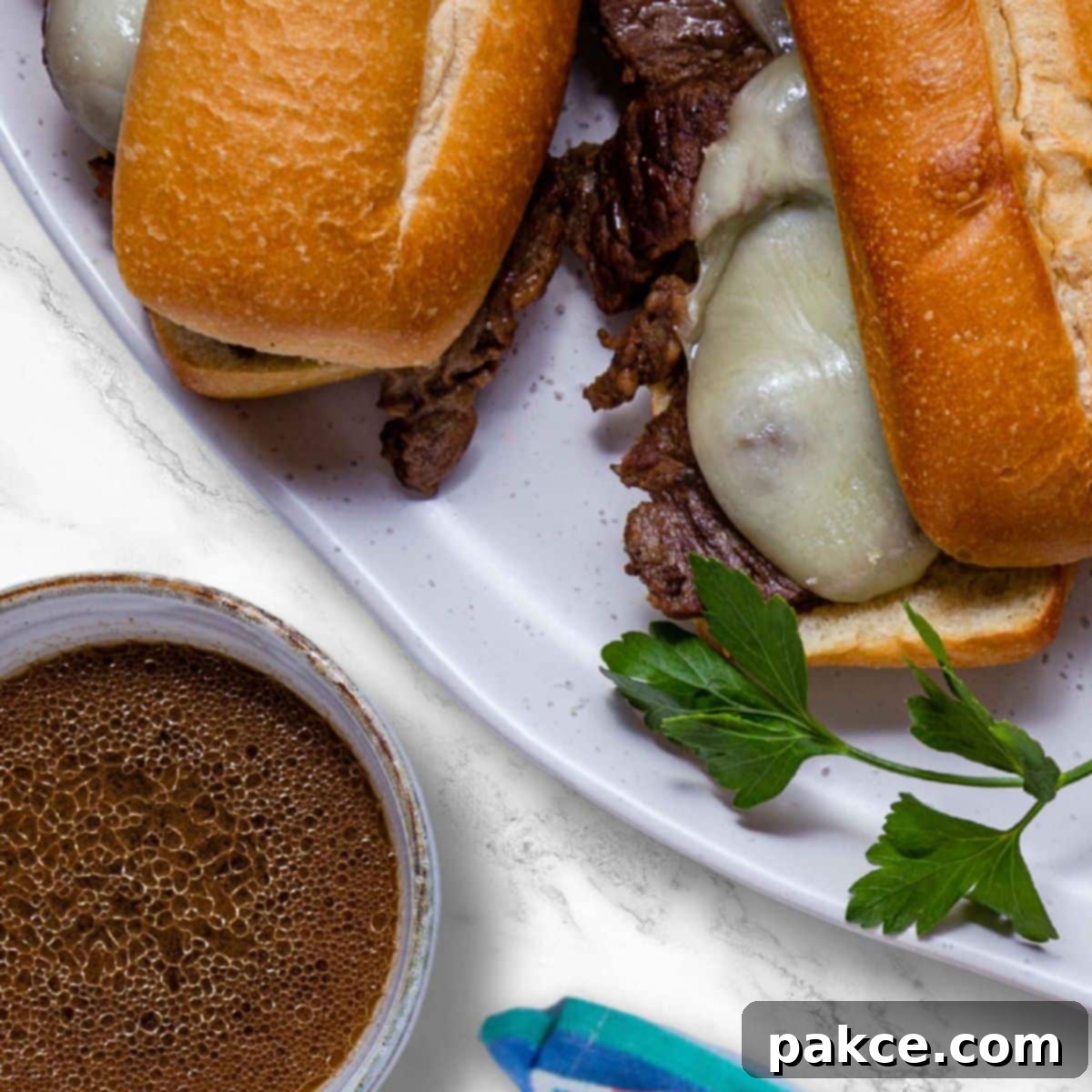 Easy Juicy Crockpot French Dip Sandwiches with Au Jus 6 Close-up of a French Dip sandwich with melted provolone cheese, tender beef, and a side of rich au jus.