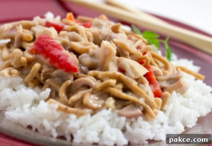 Chopped chicken with red peppers and mushrooms in a creamy sauce over white rice and garnished with chow mein noodles