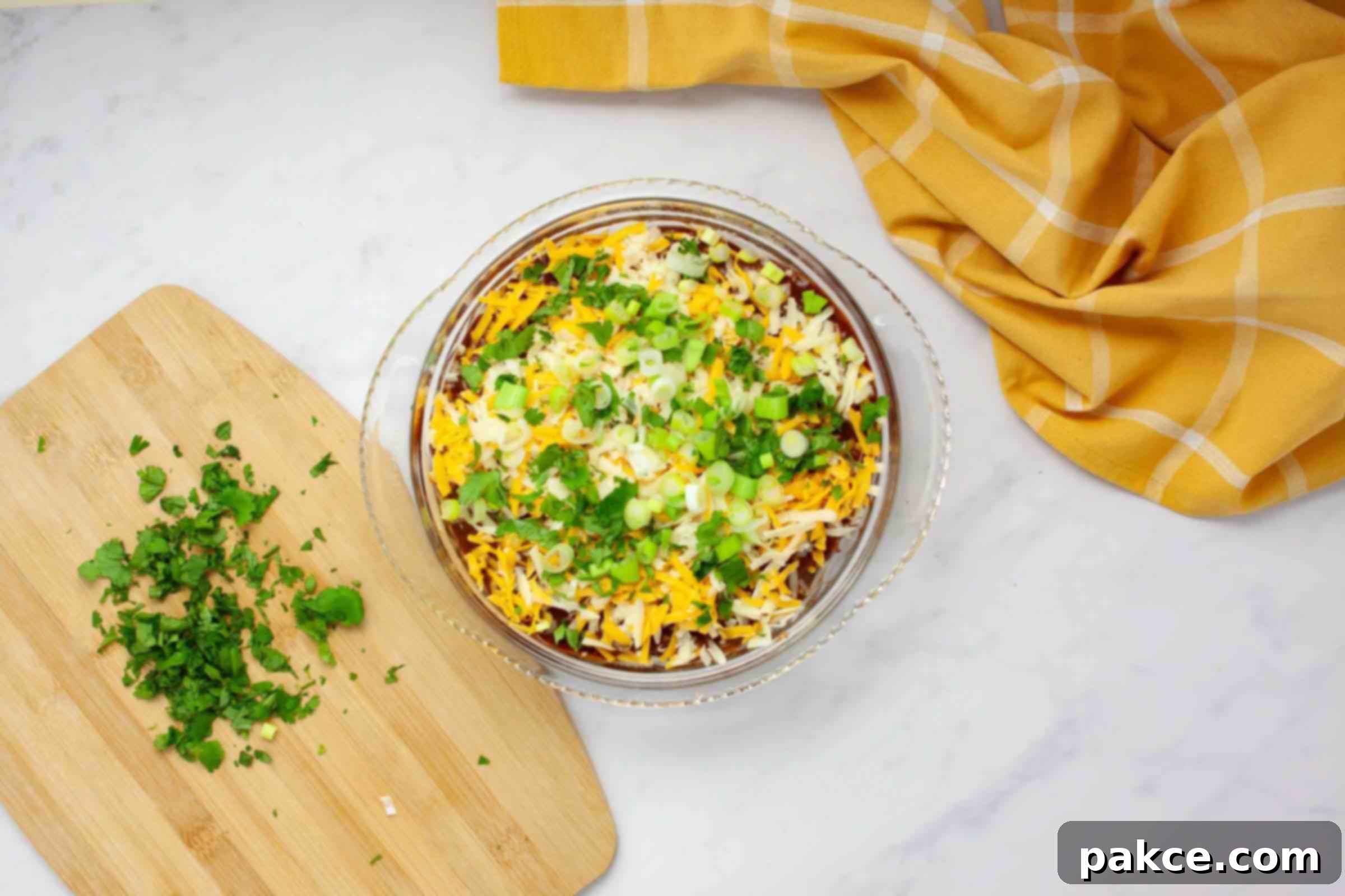 Effortless Layered Chicken Enchilada Casserole 7 Overhead view of a ready-to-bake pie dish, beautifully layered with enchilada sauce, chicken, and cheese, alternating with flour tortillas, and generously topped with vibrant green onions and fresh cilantro before it goes into the oven.