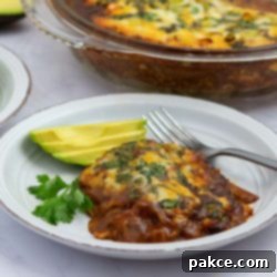 Effortless Layered Chicken Enchilada Casserole 9 A delicious single serving of layered chicken enchilada bake, beautifully plated and garnished with fresh sliced avocado, ready to enjoy.