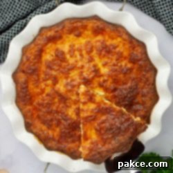 Fluffy Cottage Cheese Quiche 6 Overhead view of a slice of crustless quiche being lifted out of a pie plate, showcasing its golden crust and creamy interior.