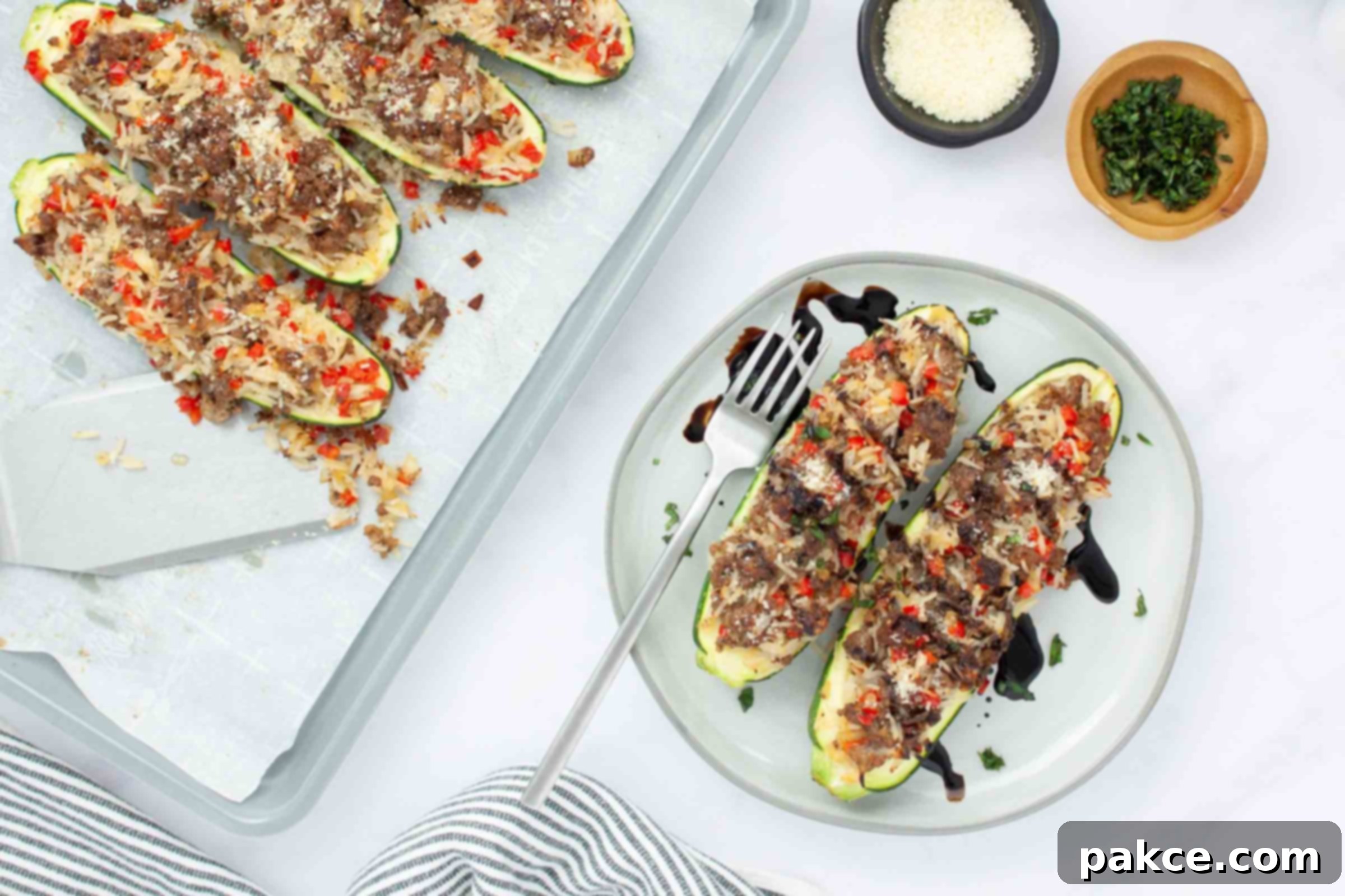 Ground Beef and Rice Stuffed Zucchini Boats 6 Baked zucchini stuffed with a rice, ground beef, and vegetable mixture drizzled with balsamic glaze on a plate next to a baking sheet lined with parchment paper with more zucchini.